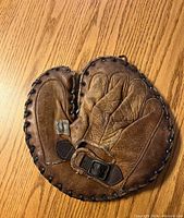 Top view of the vintage leather baseball glove showing lace border, padded fingers, and adjustable strap with buckle