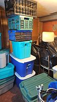 Stack of three plastic crates on top of four plastic storage bins in basement environment