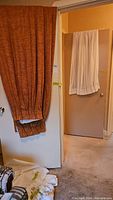 Brown kitchen curtain and white bathroom curtain hung over doors.