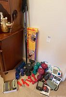 Photo displaying colorful neoprene dumbbells ranging from 3 to 10 pounds, blood pressure monitors, red hand grips, and Leki Spyder walking poles.