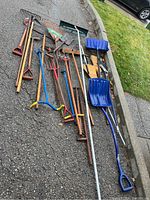 Full view of garden tools from above, showing variety of rakes, shovels, brooms, and aerators