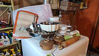 Photo showing assorted kitchenware items stacked including bowls, cookie cutters, rolling mats, and rolling pin.