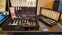 Full overview of two fitted wooden boxes containing flatware and carving set