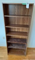 Front view of tall bookshelf with dark faux wood finish and five shelves showing wood grain patterns.