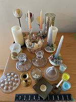 Top view of assorted candles and holders including floral ceramic holders, glass holders, pillar candles and a candle shaped like a pear.