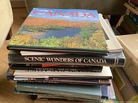 Stack of 15 coffee table books focusing on Canadian and other scenic landscapes, with visible titles including "Canada" and "Scenic Wonders of Canada"