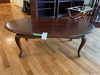 View of the oval coffee table top and legs on hardwood floor, showing size and condition.