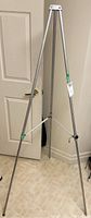 Full view of folding aluminum easel showing three legs, ribbed aluminum texture, standing extended.