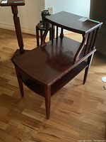Side and angled view of the wooden end table showing carved front legs, open lower shelf, and surface wear.