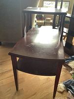 View of wood end table showing the lower open shelf and visible water marks on surface. Rectangular shape and carved front legs visible.
