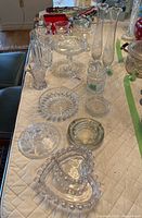 Clear crystal and glass tableware including vases, bowls, dishes, and ashtray from a wider angle showing layout.