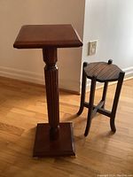 Full view of the taller Bombay Company plant stand and smaller unbranded wooden plant stand to the right, showing their size difference and finish.