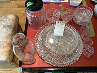 Full view of glassware lot showing lidded jar, small milk bottle, serving trays, napkin rings, butter dish, and cream and sugar set.