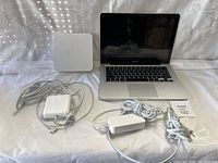 Photo of the MacBook Pro laptop, AirPort Express, and two Apple power adapters on white background.