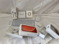 Overview of all items in the lot including keyboard, mouse, AirPods, cables, and original boxes of iPhones and accessories.