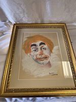 Framed clown portrait artwork by Robert Clayton with orange hair and white ruffled collar.