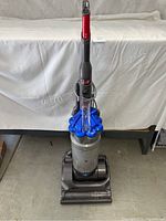 Front view of upright Dyson vacuum cleaner showing dust container and base.