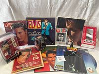 Photo showing Elvis memorabilia including LIFE magazines, Elvis figurine, Elvis Illustrated Collector's book, TV Guide, vinyl record, and other small collectible items