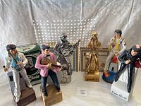 Overall collection of five Elvis Presley decanters and figurines on display with certificates in background