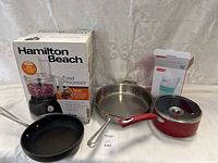 Hamilton Beach food processor in box displayed with accompanying pans and cup