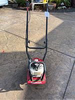 Top view of Honda rototiller showing handlebars, fuel tank, and red base with Honda branding.