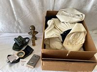 Photo of lot including beige military uniform, two brass bust statues, green binoculars with case, naval buttons sealed packet, and circular slide rule device.