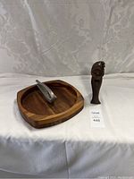 Photo shows walnut divided wooden bowl, metal nutcracker on top, and wooden figurine nutcracker side by side.
