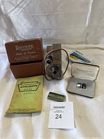 Vintage Revere Model 88 8mm movie camera with original box and accessories on white sheet background