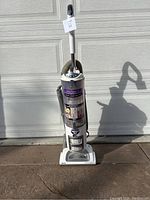 Full view of Shark Navigator Professional upright vacuum in white with clear dust cup and hose attachment, standing upright on pavement.