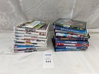 Stack of Wii game cases showing titles including Just Dance 4, Carnival, Game Party and others, and a stack of DVD movies including E.T., Dumbo, Finding Nemo, and Marmaduke.