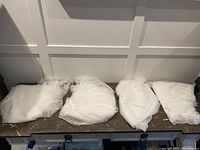 Four white curtains laid out on a surface, showing fabric texture and length.