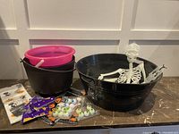 Overview of Halloween decorations including three plastic buckets, a white skeleton figure, and packs of plastic eyeballs.