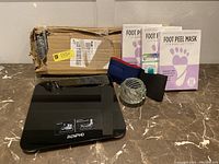 Lot contents showing towel bar in packaging, RENPHO bathroom scale, three foot peel masks, glass votive candle holder, and headgear.