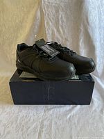 Pair of new black men's Reebok steel toe running shoes on top of box with tags attached.