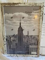 Front view of rustic picture frame with placeholder image of a city skyline including the Empire State Building. Frame shows weathered wood finish in white and brown.