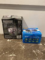 Photo of the Eliminator spotlight box and the mini laser stage light box side by side on a marble surface.