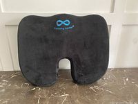 Front view of black memory foam seat cushion with blue 'Everlasting Comfort' logo on top.