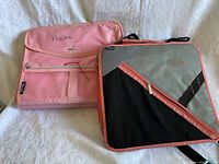 Both zippered binders shown side by side on a white surface. Pink binder with embroidery on left, Thule binder on right.