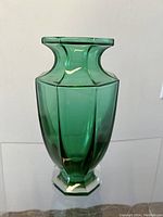 Front angled view of facetted emerald green art glass vase showing baluster form and hexagonal base