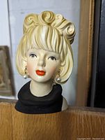 Front view of the porcelain or ceramic head vase figurine showing blonde hair, painted facial features, red lips, and pearl drop earrings.