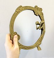 Photo of the full circular mirror showing the brass frame with the Art Nouveau female figure and floral decorations.