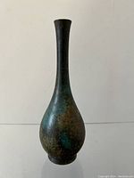 Side view of a tall bronze baluster form vase with textured aged patina and slender neck