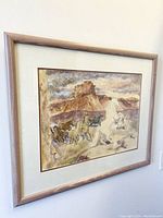 Angled view of framed watercolor painting showing horses and canyon landscape
