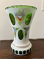 Front view of vintage Bohemian art glass vase showing hand-painted floral designs and green oval glass panels with gold scrollwork.