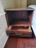 Photo of one wooden night table showing open drawer and large open storage compartment above it.