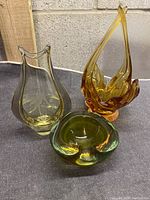 Photo showing all three Murano glass items - green ashtray, yellow etched vase, and orange sculptural vase arranged together
