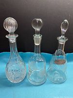 Front view of three vintage decanters showing distinctive styles and glass details on a blue fabric background.