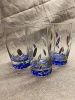 Three vintage handblown glasses with millefiori murrine spots and blue bases on a fabric background