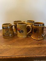 Five Wade vintage beer mugs displayed together showing their varied Veteran Car Club of Great Britain designs and silver trimming on handles and rims.