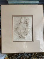 Framed etching print of a baby from behind, with visible line work and geometric details.